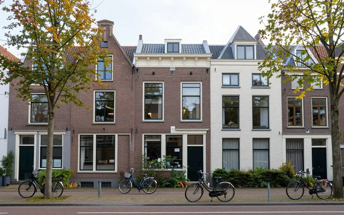 Rij grachtengevels met stoepen en fietsen langs het water